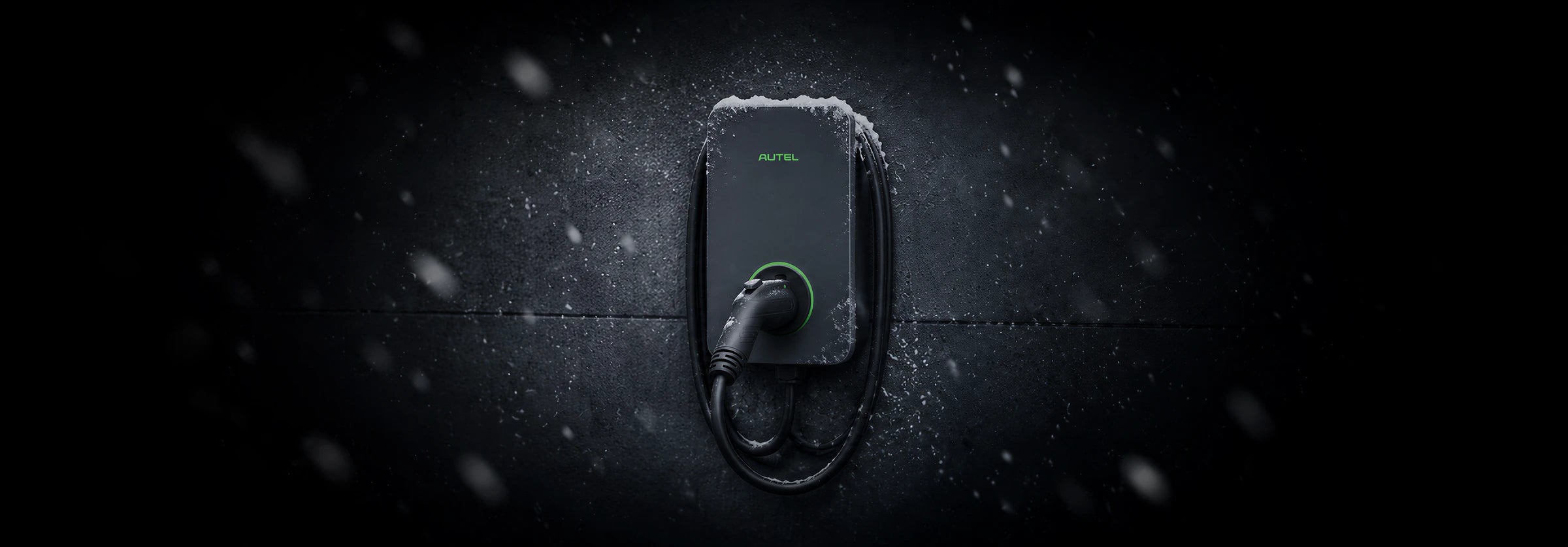 The Autel charger mounted outdoors with snow on its housing and snowflakes in the air